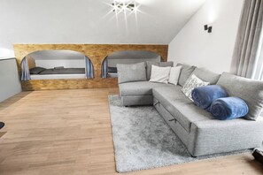 Moderni makuuhuone, jossa on parivuode, harmaa sohva ja puulattia.