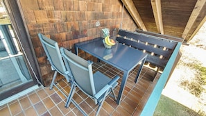 An outdoor patio with a table and chairs, a wooden wall, and a tiled floor. - Cozy living room with a fireplace and a tiled stove, featuring two balconies in Oberstaufen (Oberstaufen)