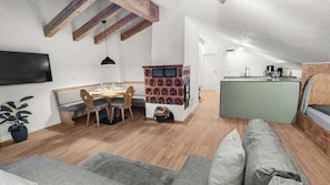 A compact living space with a dining area, kitchenette, and seating area. - Cozy living room with a fireplace and a tiled stove, featuring two balconies in Oberstaufen (Oberstaufen)