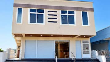 A two-story building with a flat roof, large windows, and a front entrance with steps leading up to it.