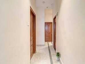 A corridor with wooden doors and a potted plant.
