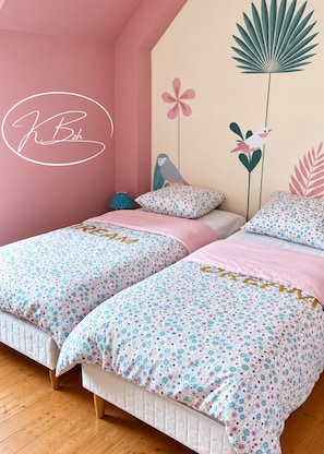 A bedroom with two beds, floral bedding, a wall with wall art, and a pink accent wall. - Hélène's house for 2 to 4 people with a garden, 15 minutes from the ocean (Gommenec'h)