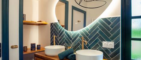 A bathroom with two sinks, a mirror, and a herringbone-patterned wall.