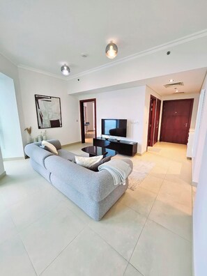A modern living room with a grey sofa, a black coffee table, and a flat-screen TV. - Elegant 1BR apartment in Burj Vista, steps to Iconic Burj Khalifa and Dubai Mall (Dubai)