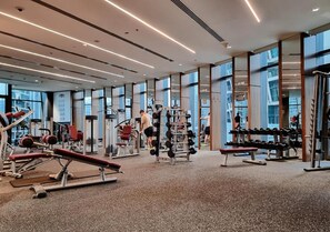Une salle de sport équipée de divers appareils d’exercice, dotée de grandes fenêtres et présentant un aménagement intérieur moderne.