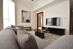 Ein modernes Wohnzimmer mit einem grauen Sofa, einem schwarzen Couchtisch und einem flachbildfernseher an der Wand.