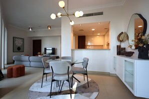 Ein modernes Wohnzimmer mit einem grauen Sofa, einem runden Glastisch mit Stühlen und einer Deckenleuchte.