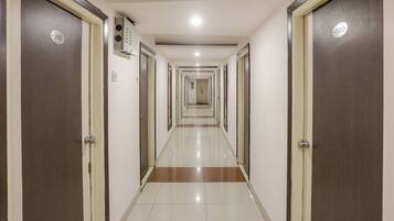 Un couloir d’hôtel avec les portes numérotées 302 et 310, un détecteur d’incendie et un sol carrelé.