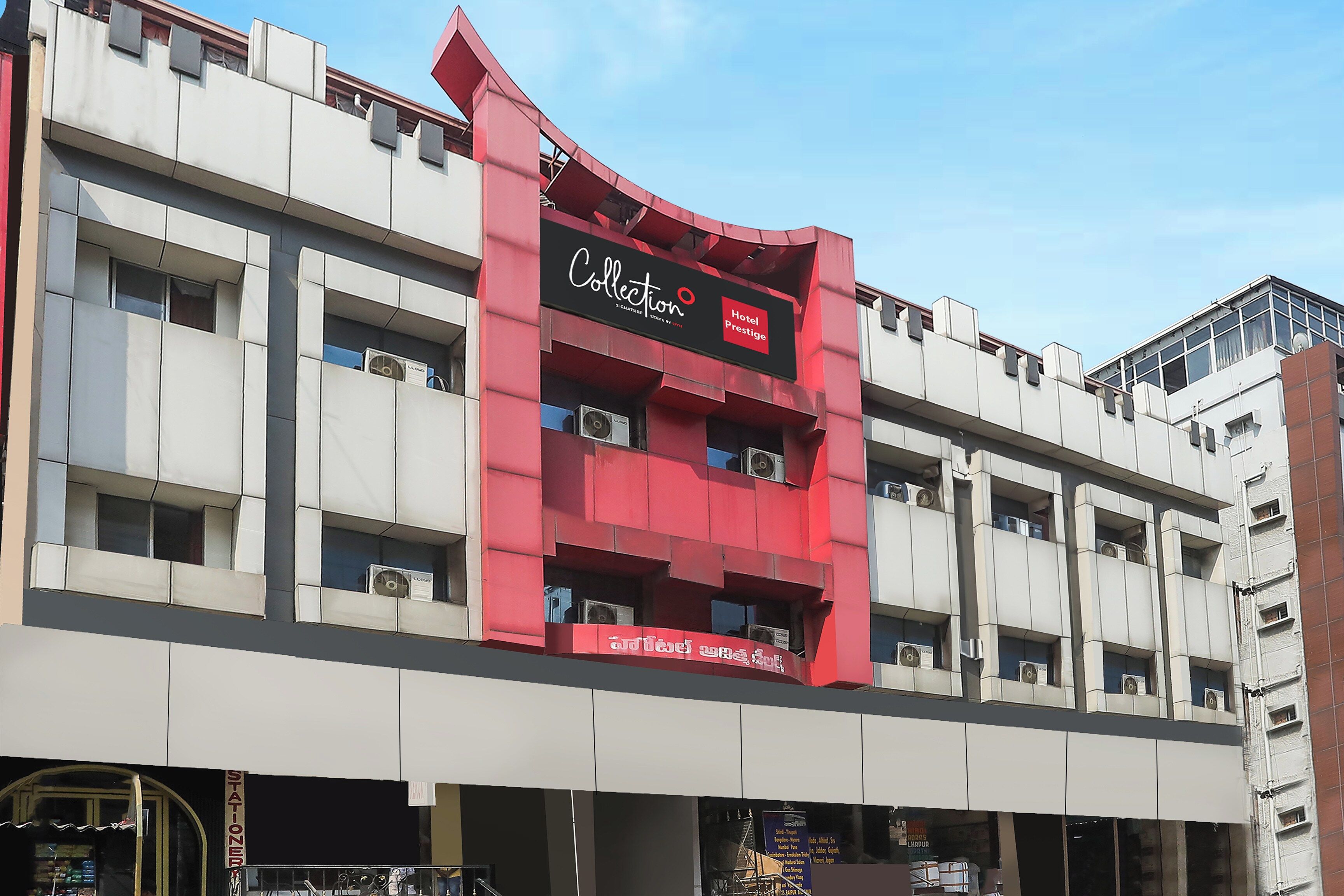 Edifício de hotel com fachada marcante em vermelho e branco, diversas varandas e placa indicando ser um Hotel Collection Prestige.