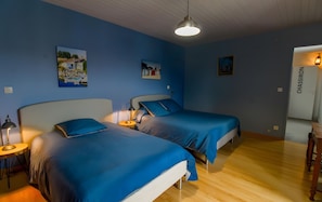 Ein Zimmer mit zwei Betten, einem Schreibtisch und einem Stuhl. An der Wand befinden sich Gemälde und eine Tür mit der Aufschrift 'CHASSIRON'.