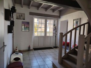 A room with a tiled floor, a staircase, a door with a window, and a coat rack.