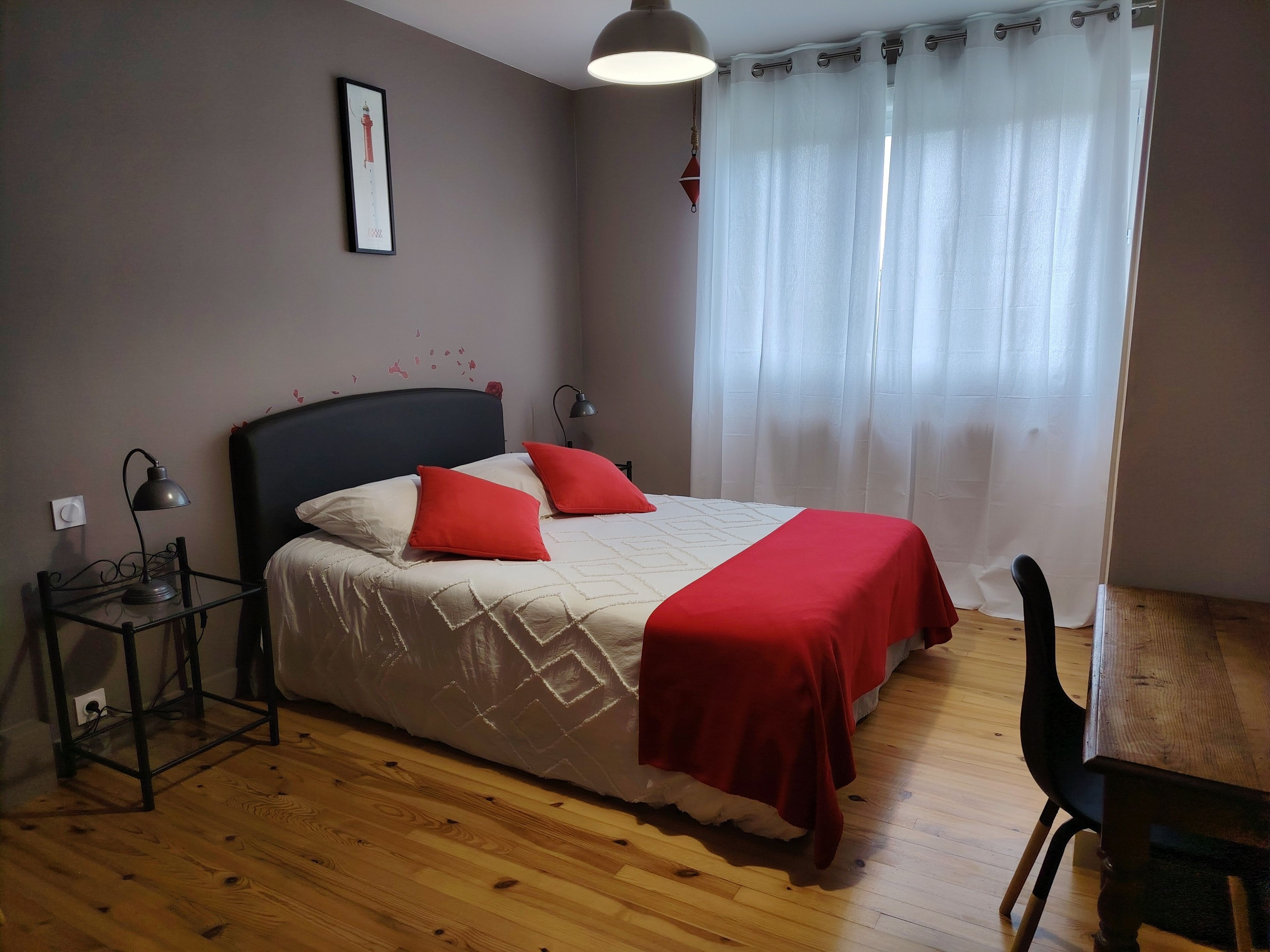 Ein Schlafzimmer mit einem Bett, Nachttischlampen, einem Schreibtisch und einem Stuhl.