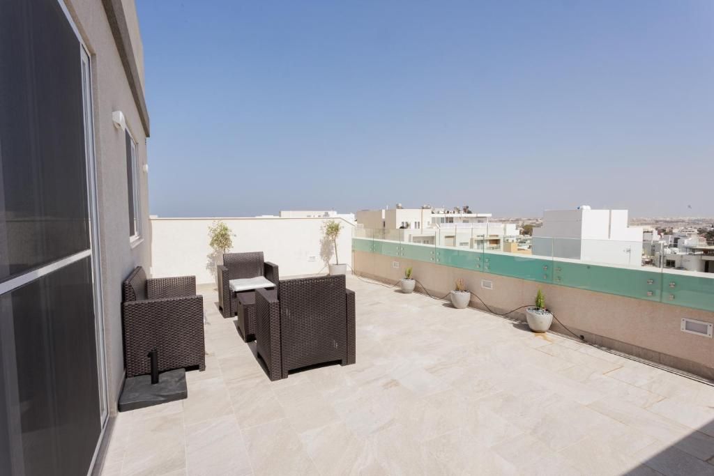 Una terraza en la azotea con mobiliario exterior, plantas en macetas y vistas de la ciudad.