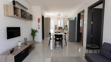 Ett modernt vardagsrum med en platt-TV, en träkonsol och en grå soffa.