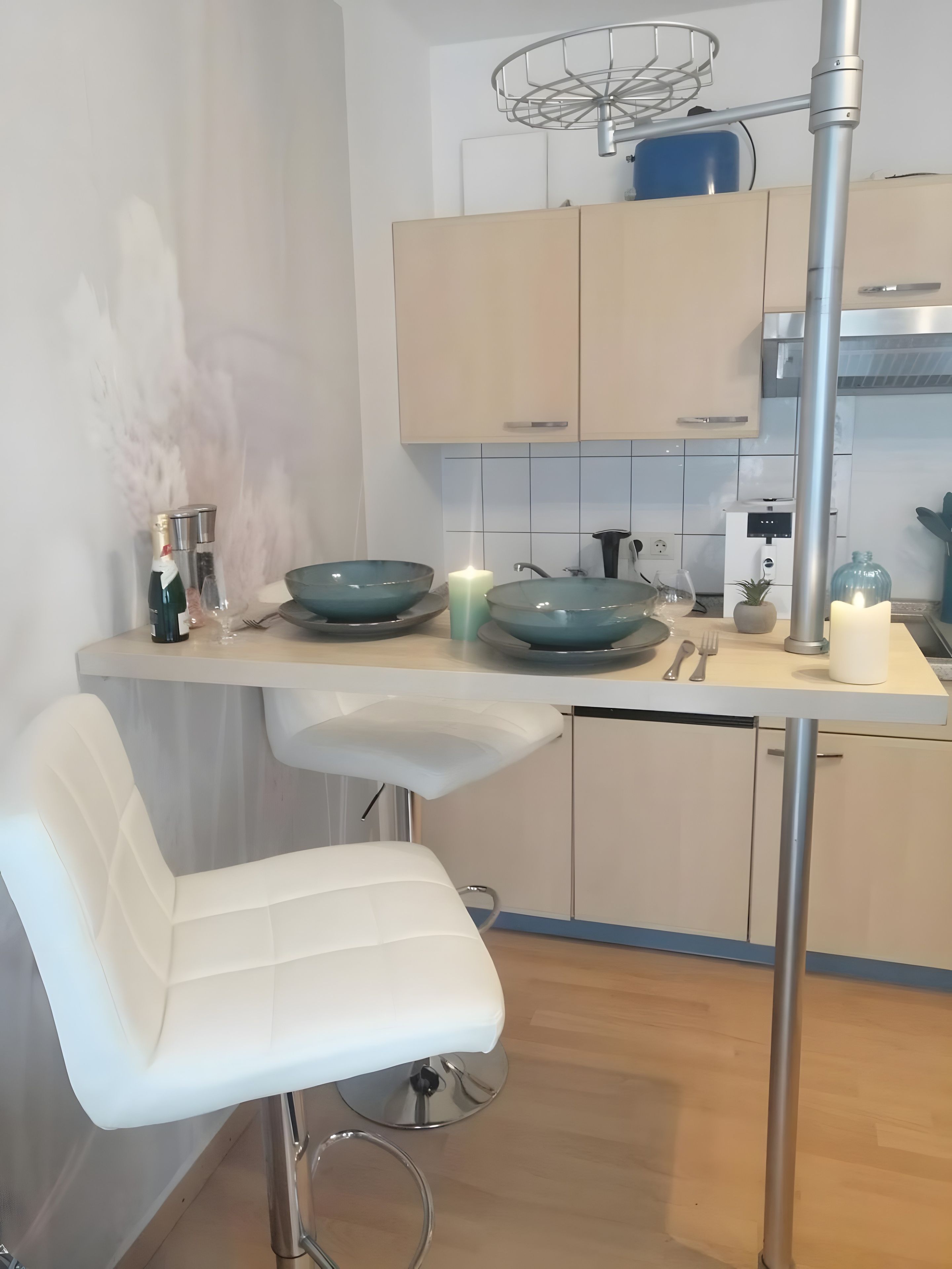 Una cocina moderna con dos taburetes blancos, un lavaplatos empotrado y una mesa de comedor.