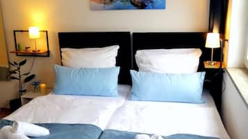 Una cama doble con dos almohadas, una mesita de noche con una lámpara y un cuadro en la pared.