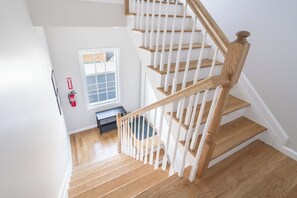 Eine Holztreppe mit weißen Geländern, die zu einer oberen Etage führt.