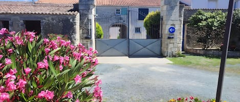 A gated entrance with a stone wall, a metal gate, and a blue directional sign.