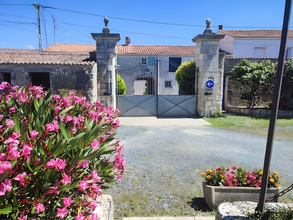 A gated entrance with a stone wall, a metal gate, and a blue directional sign.