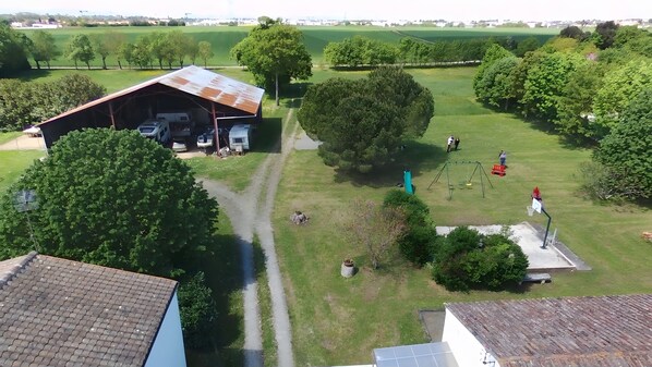 A rural property with a large barn, a grassy field, and a swing set.