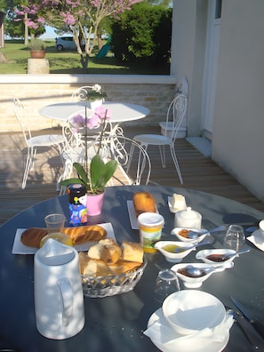 Une table dressée à l’extérieur, avec une variété de plats, une cafetière et une plante en pot.