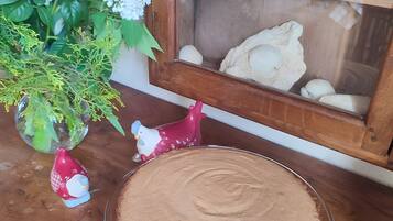 A dessert plate on a wooden table, a vase with flowers, and a toy tractor in a window.
