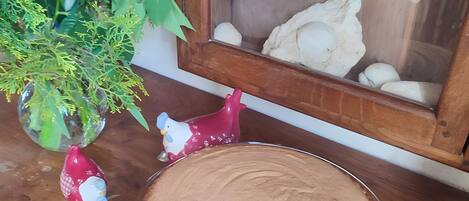 A dessert plate on a wooden table, a vase with flowers, and a toy tractor in a window.