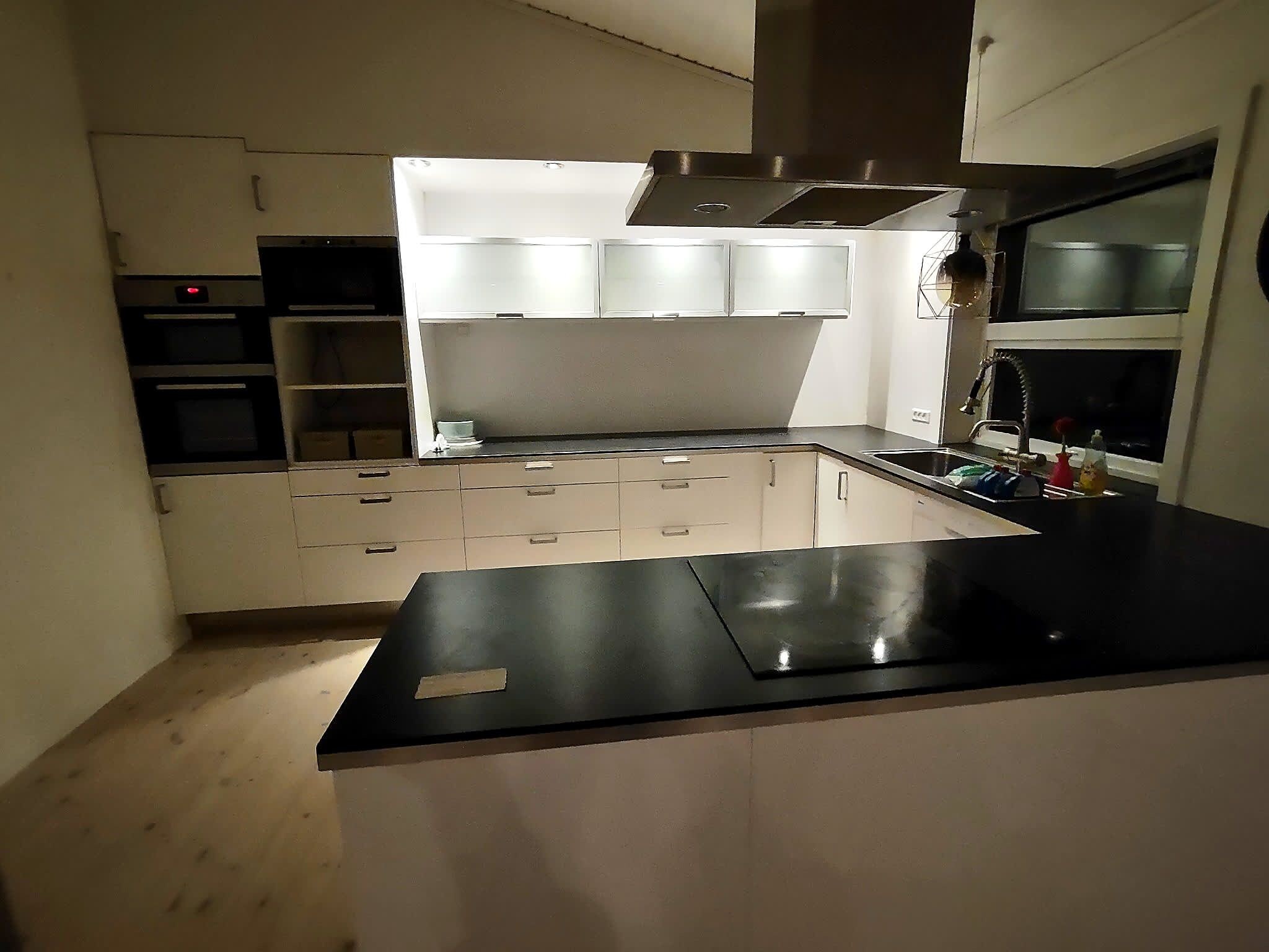 A modern kitchen with white cabinets, a black countertop, and stainless steel appliances.