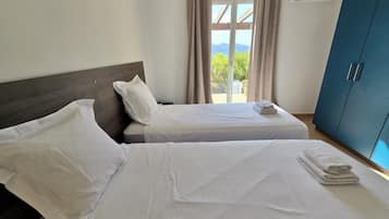 Habitación de hotel con dos camas, un armario y vistas al exterior.