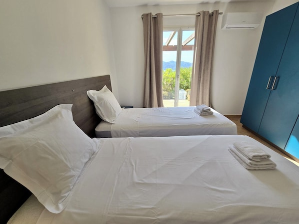 Habitación de hotel con dos camas, un armario y vistas al exterior.