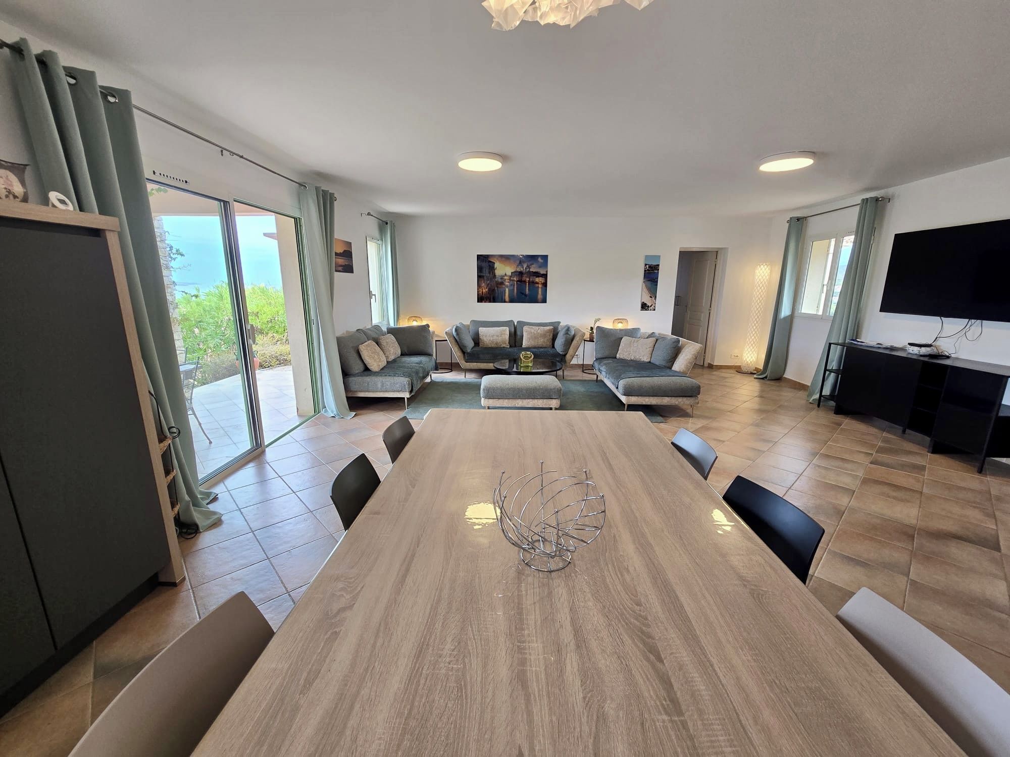 Un espacio habitable amplio con un gran comedor de madera, un conjunto de sofás y un televisor.