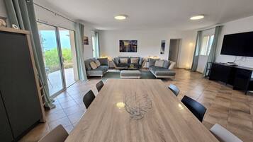Un espacio habitable amplio con un gran comedor de madera, un conjunto de sofás y un televisor.