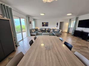 Un espacio habitable amplio con un gran comedor de madera, un conjunto de sofás y un televisor.