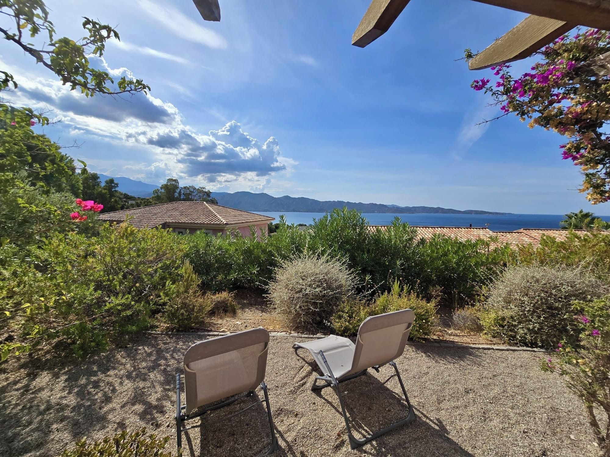 A patio with two chairs facing a scenic view of a lake and mountains.