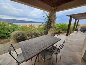 Un patio exterior con mesa y sillas, con vistas a un cuerpo de agua y montañas.