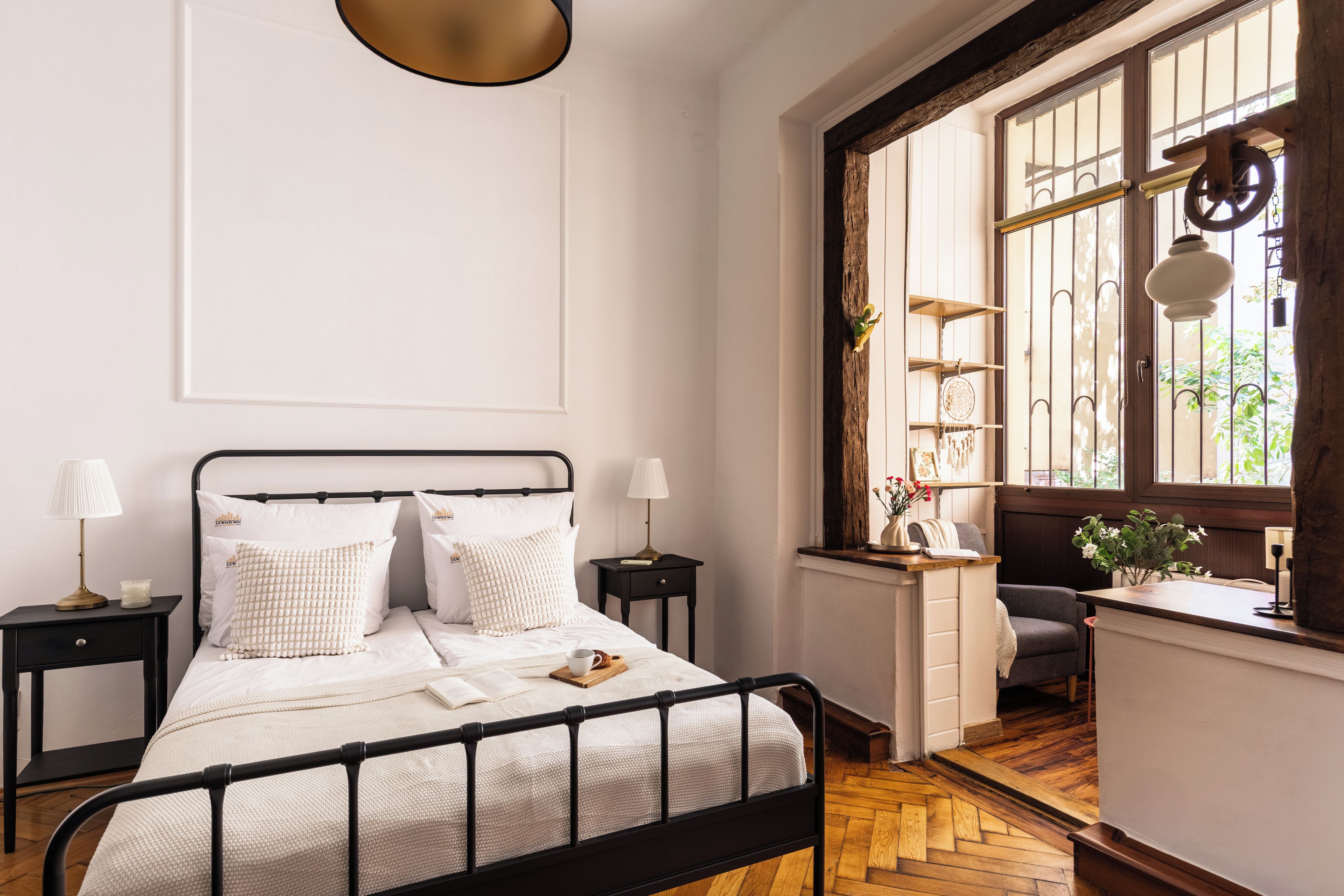 A bedroom with a bed, bedside tables, a window with a view, and a desk area.