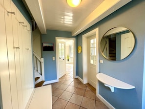 A hallway with a white door, a round mirror, and a white shelf. - Westerhus Nieblum (Nieblum)