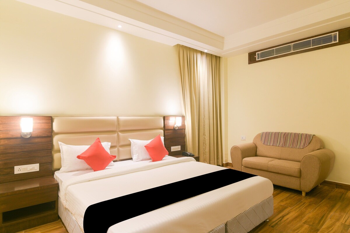 Una habitación de hotel con una cama, una silla y una mesita de noche.