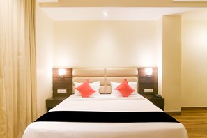 Une chambre d’hôtel avec un grand lit, deux tables de chevet, un plancher en bois et une tête de lit dotée d’un éclairage intégré.