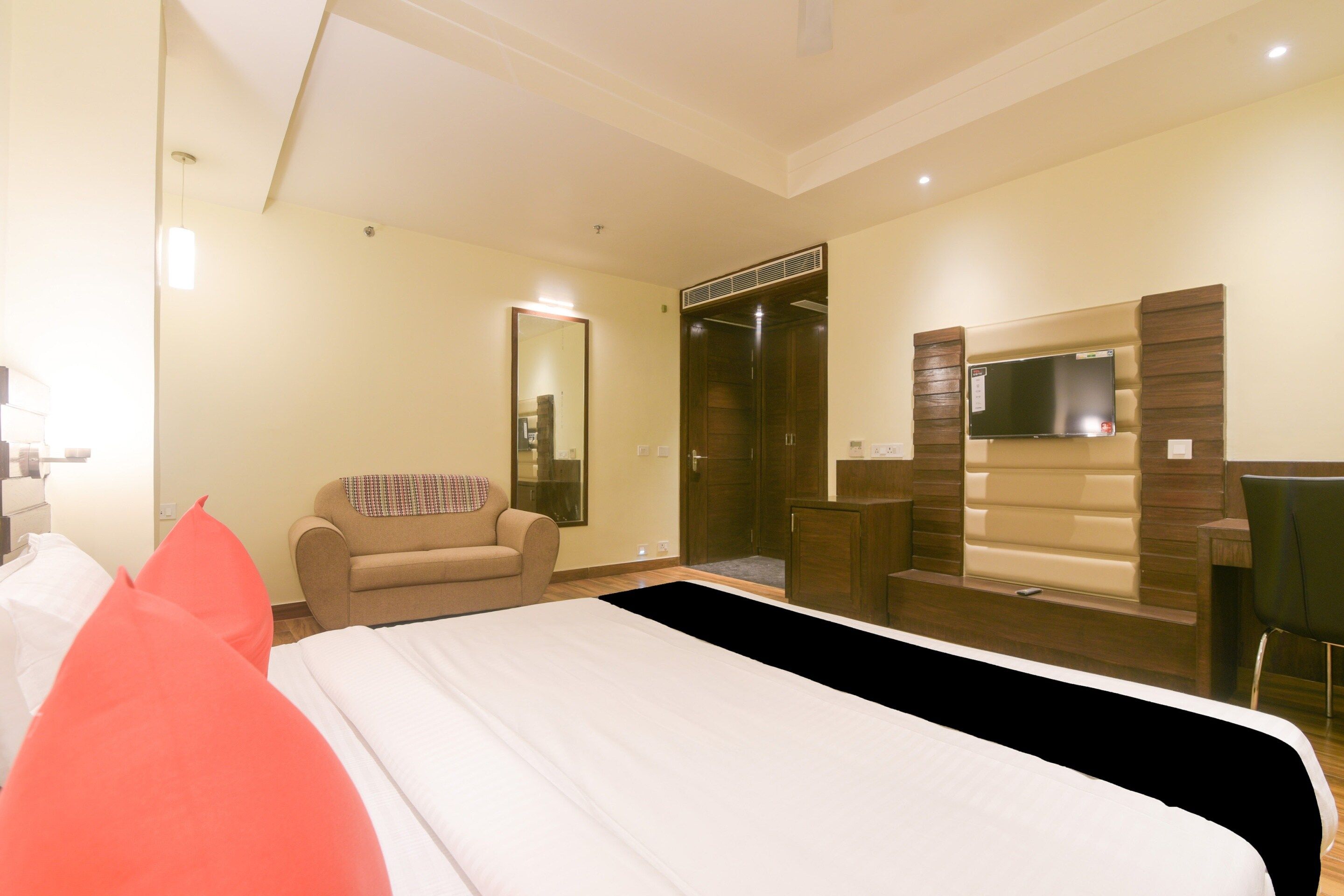 A hotel room with a bed, a chair, a wardrobe, and a television.