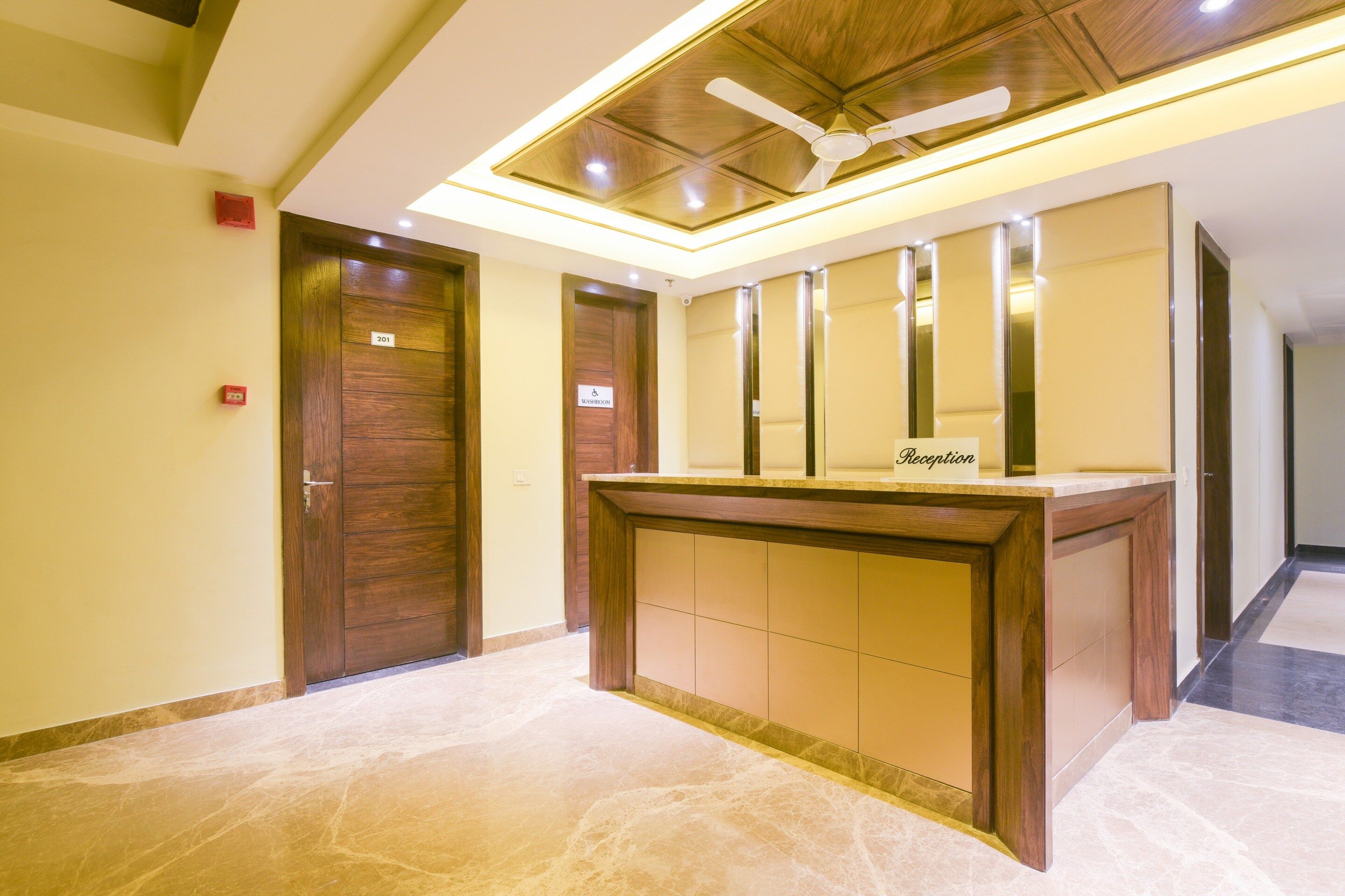 A reception desk with a sign, a ceiling fan, and a wooden door labeled '201'.