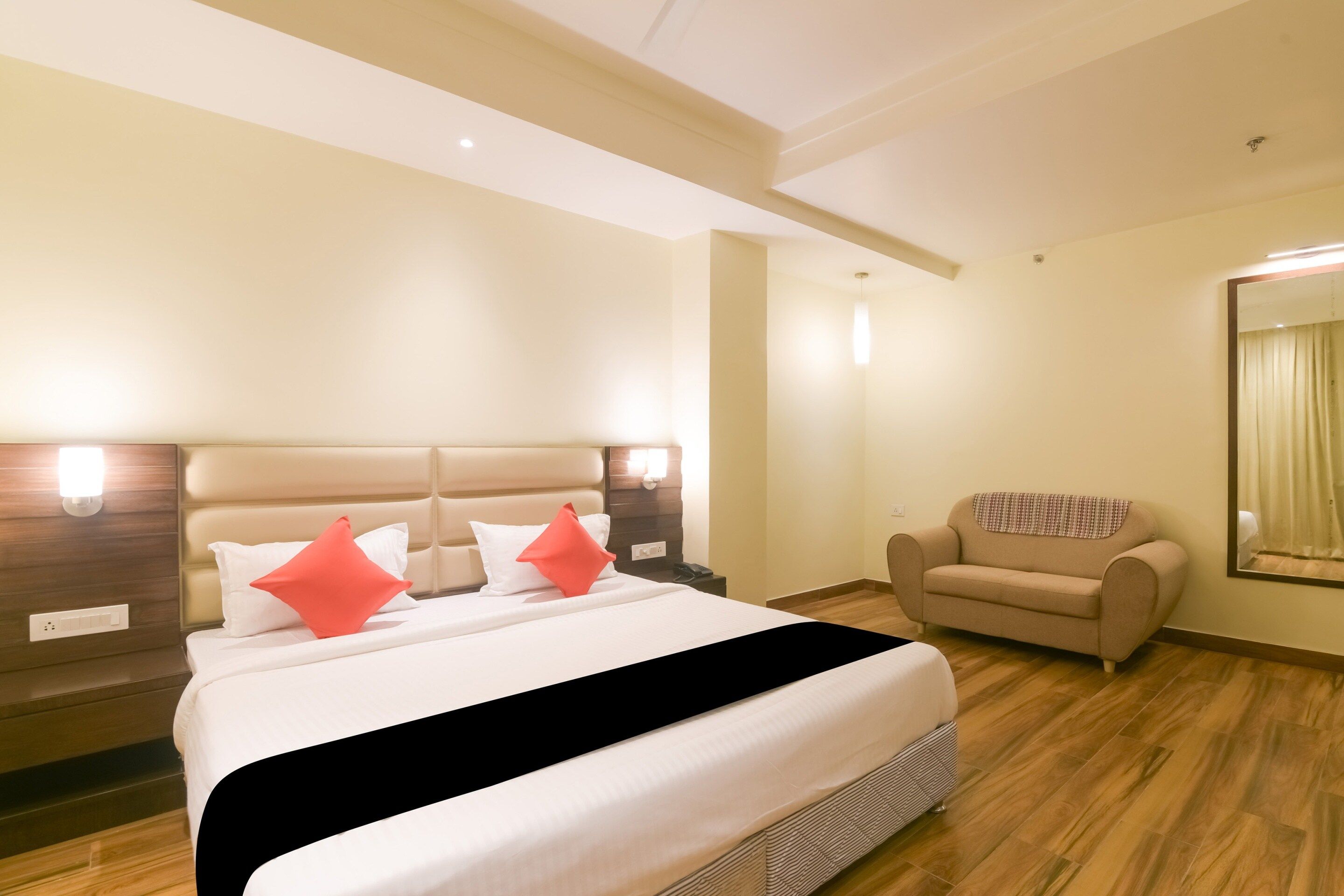 A hotel room with a bed, a chair, and a mirror.