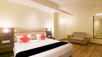 A hotel room with a bed, a chair, and a mirror.