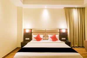 Quarto de hotel com uma cama grande, duas mesas de cabeceira e um criado-mudo com telefone, e uma cortina.