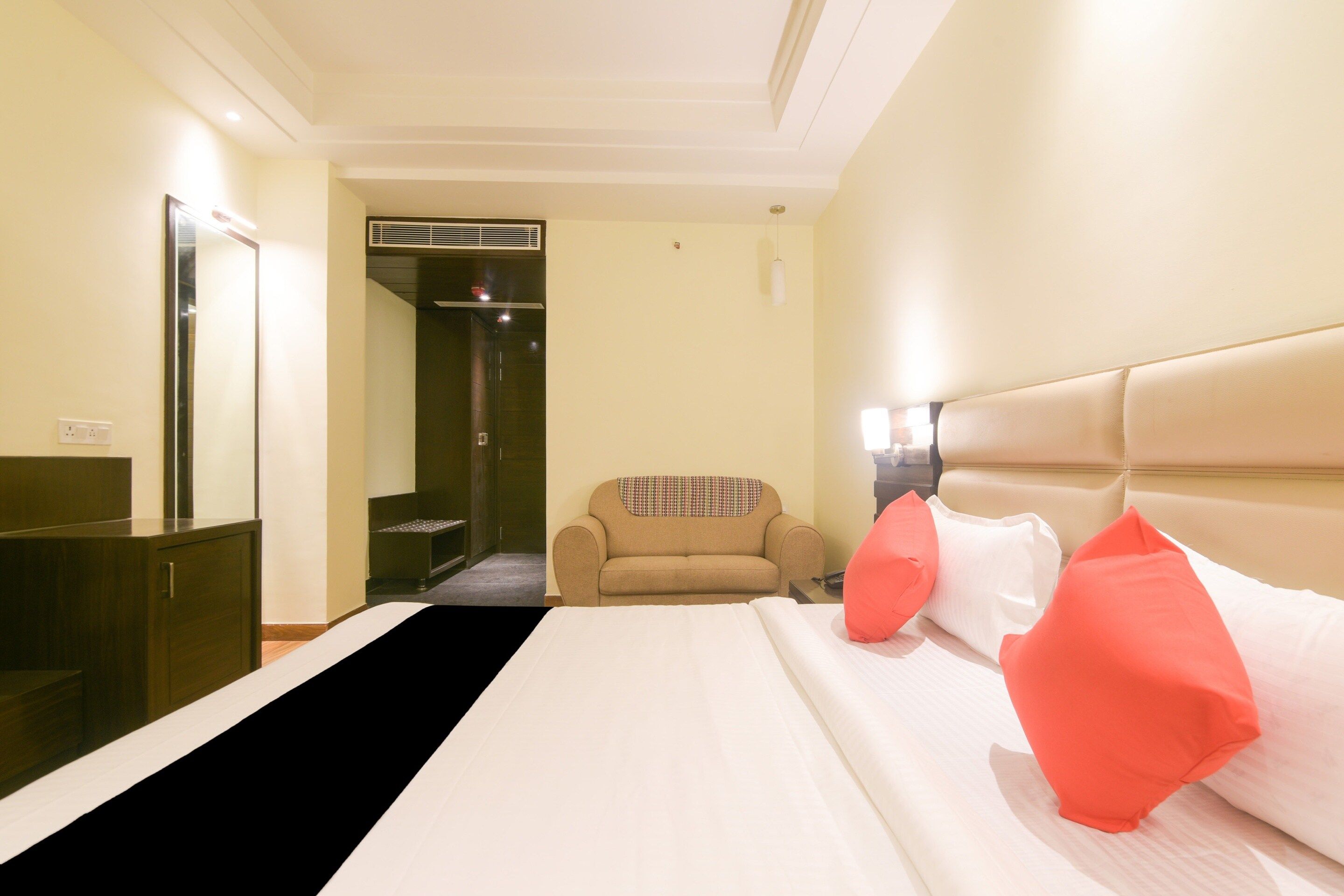 A hotel room with a bed, a sofa, a desk, and a mirror.