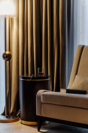 A modern room with a sofa, a side table with a glass, and a lamp. - Hotel Experior Grand - Destigo Hotels (Gdańsk)