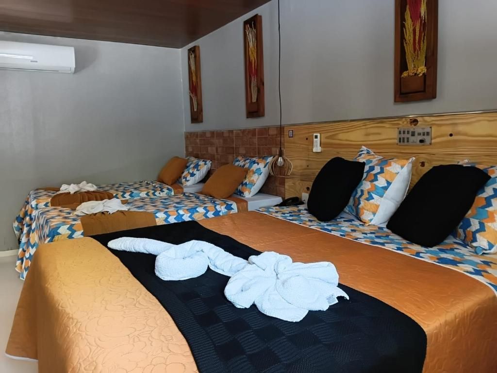 Habitación de hotel con dos camas, cada una con ropa de cama y almohadas estampadas, cabecero de madera y aire acondicionado instalado en la pared.