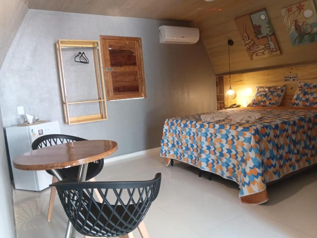 Un dormitorio con una cama, cabecera de madera, una mesa con sillas y un aire acondicionado instalado en la pared.