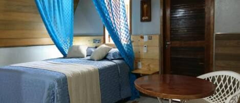 A bedroom with a bed, a bedside table, a chair, and a window with curtains.