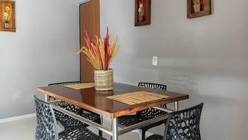 Un comedor con una mesa de madera, sillas negras y un florero con flores secas.